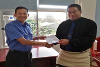 Minister of Public Enterprises Hon. Poasi Tei (right) receiving dividend from CEO of TCC Mr. Rizvi