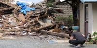 A man in front of a collapsed residence where his mother is trapped after Japan earthquake last week. (Photo by BBC)